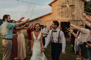 Wedding celebration with guests dancing under string lights at a rustic barn venue.