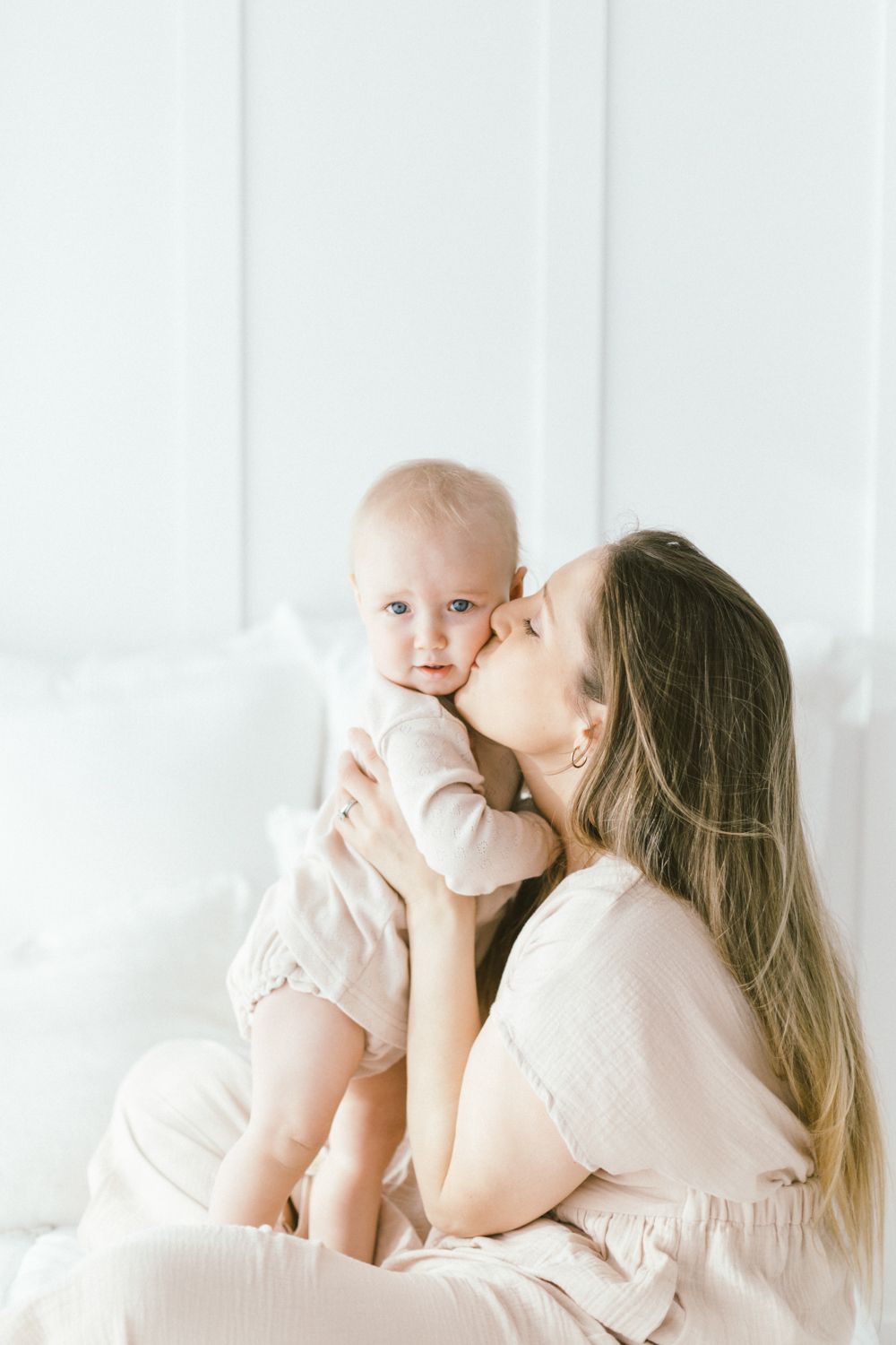 Loving interaction between parent and infant in soft beige tones.