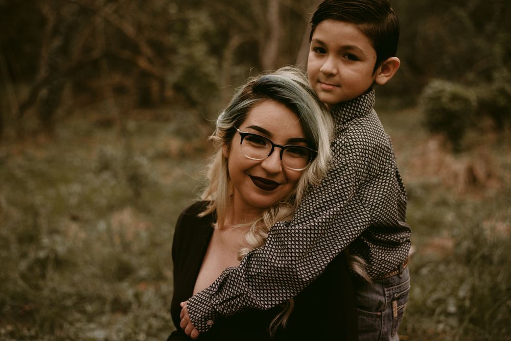 A playful outdoor portrait showing affectionate interaction between two people against a natural backdrop.