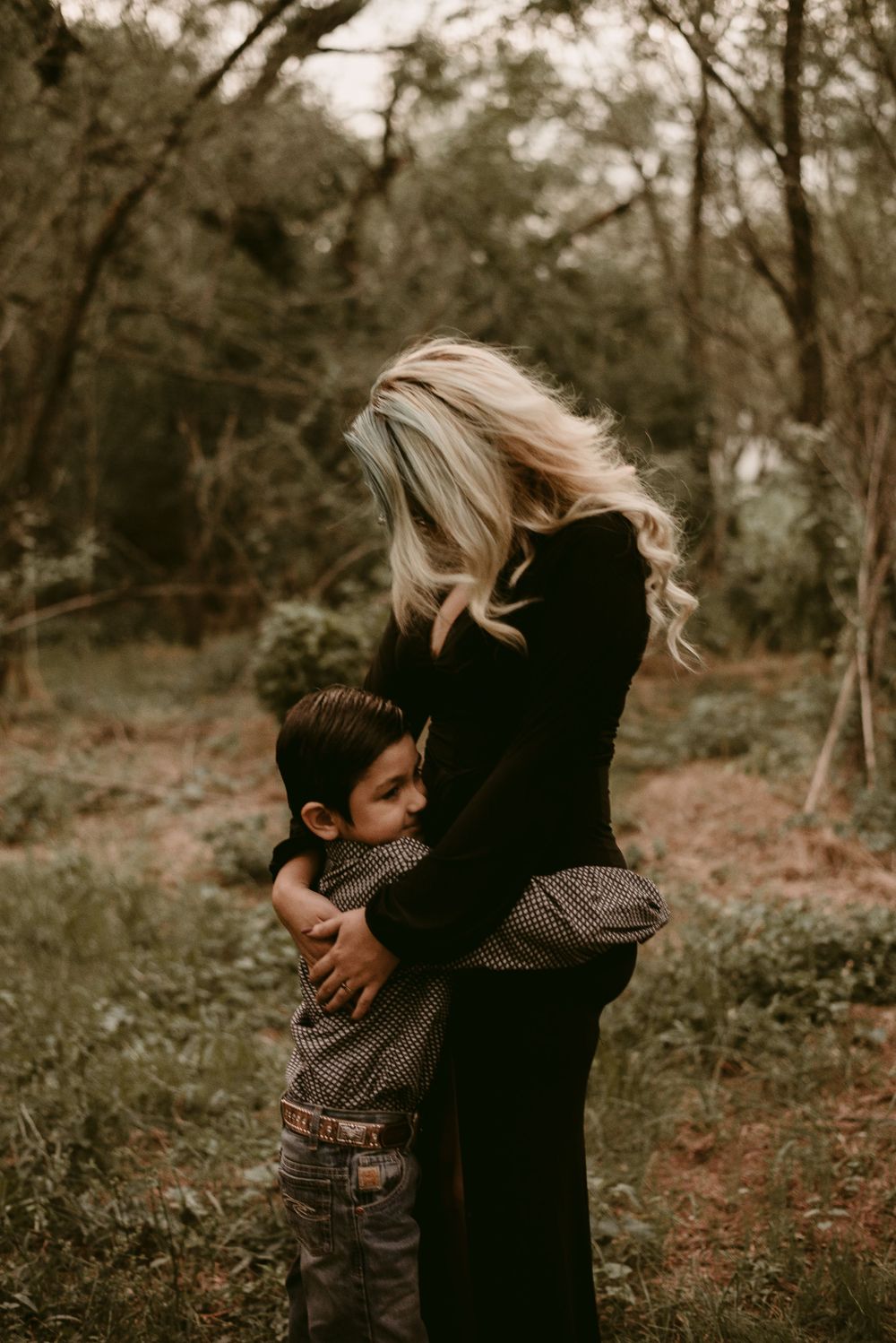 A touching autumn forest moment showing an embrace between a long-haired figure in black and a small child.