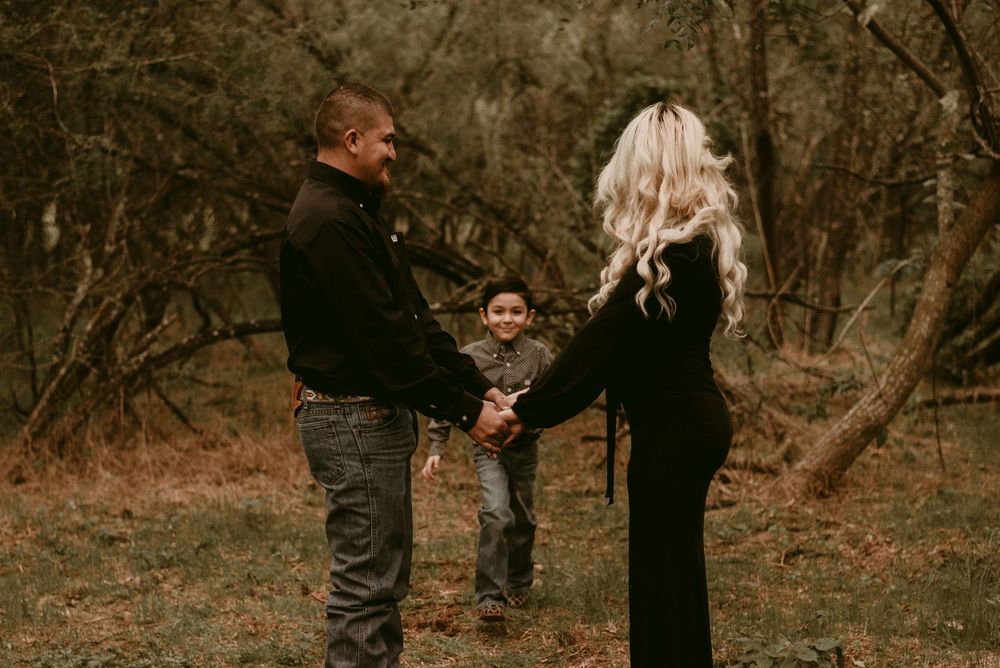A candid moment captured of three people holding hands together in a wooded setting.