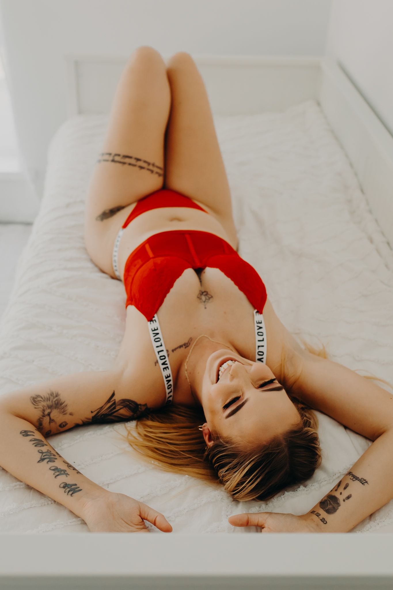 Artistic portrait photo of red lingerie on white bed.