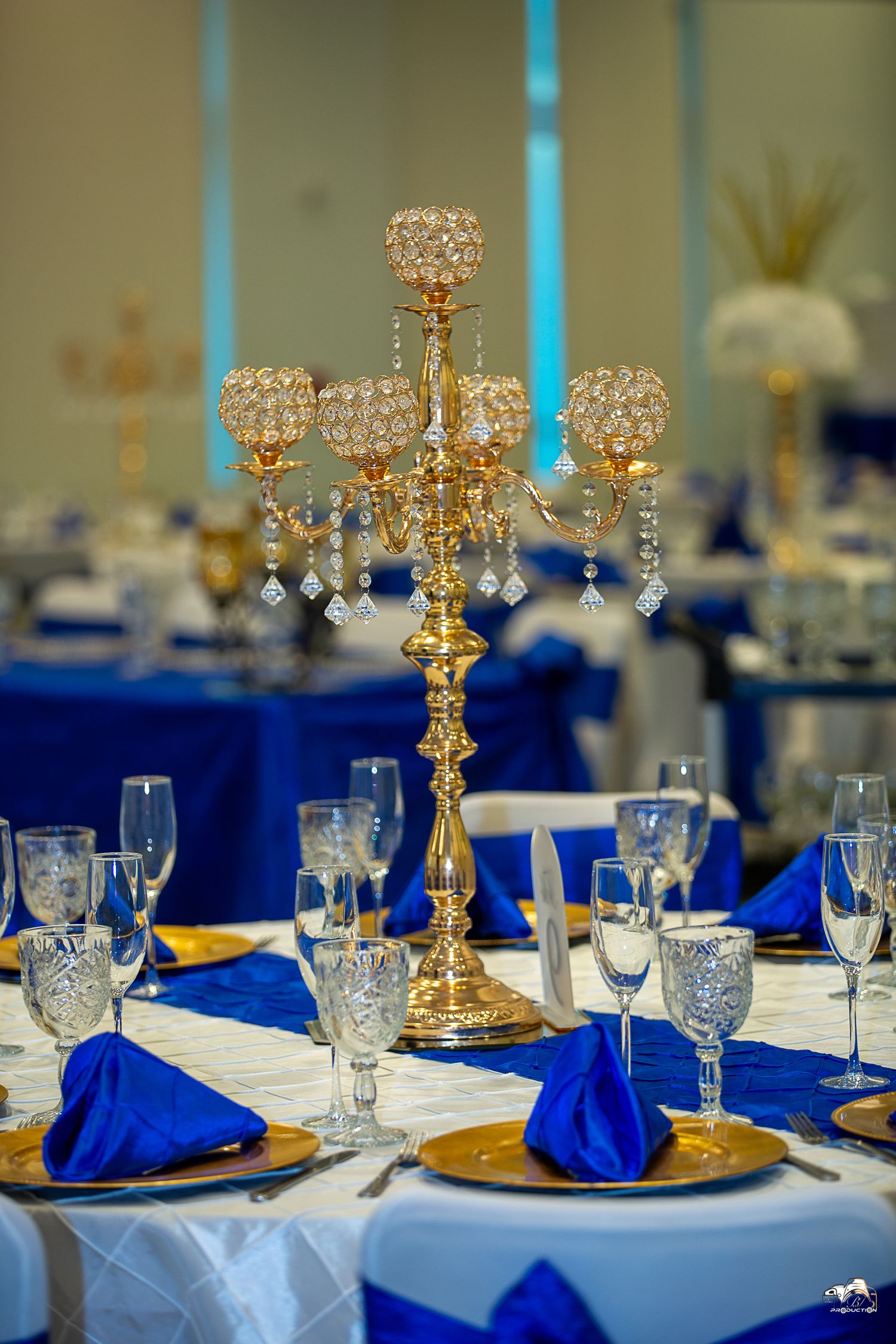 An elegant gold candelabra centerpiece on a table with blue and white formal place settings.