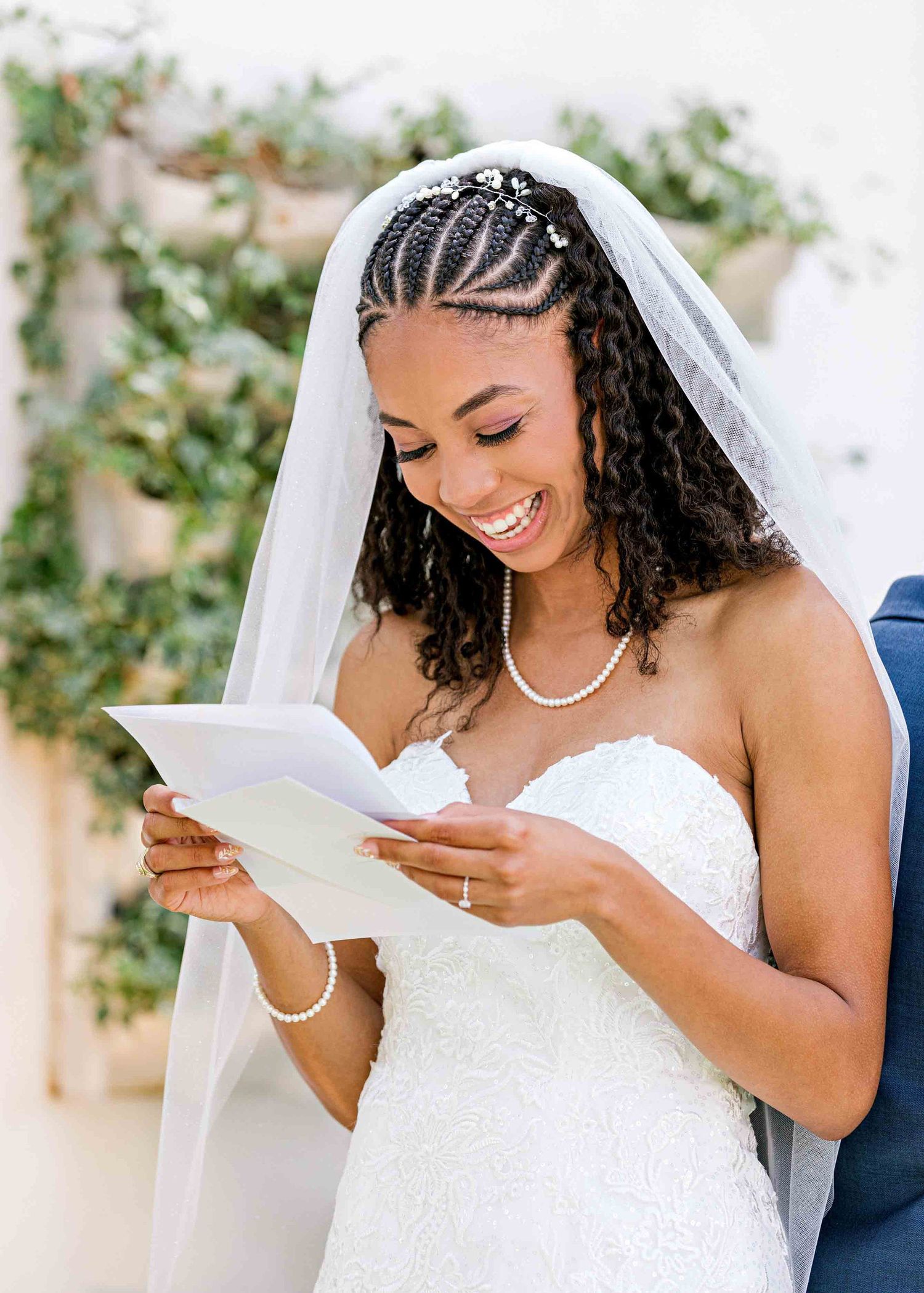 A beautiful bride in a white wedding dress reading from a paper with a joyful expression.