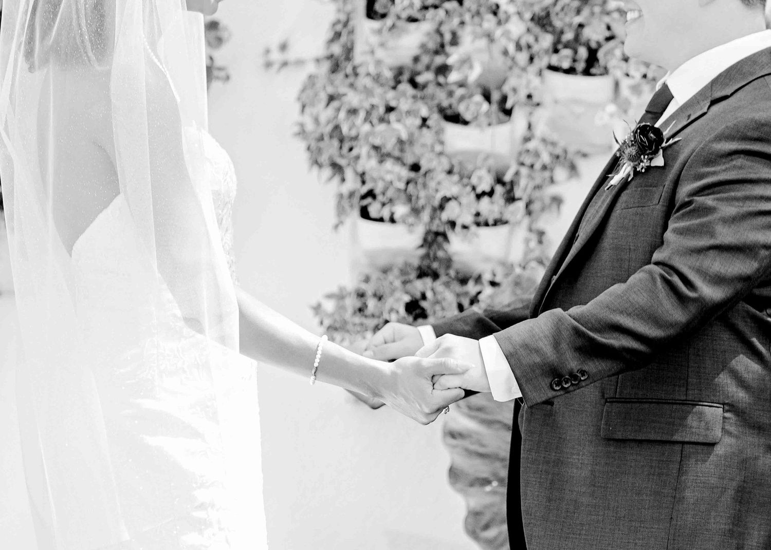Black and white image capturing an intimate moment during wedding vow exchange.