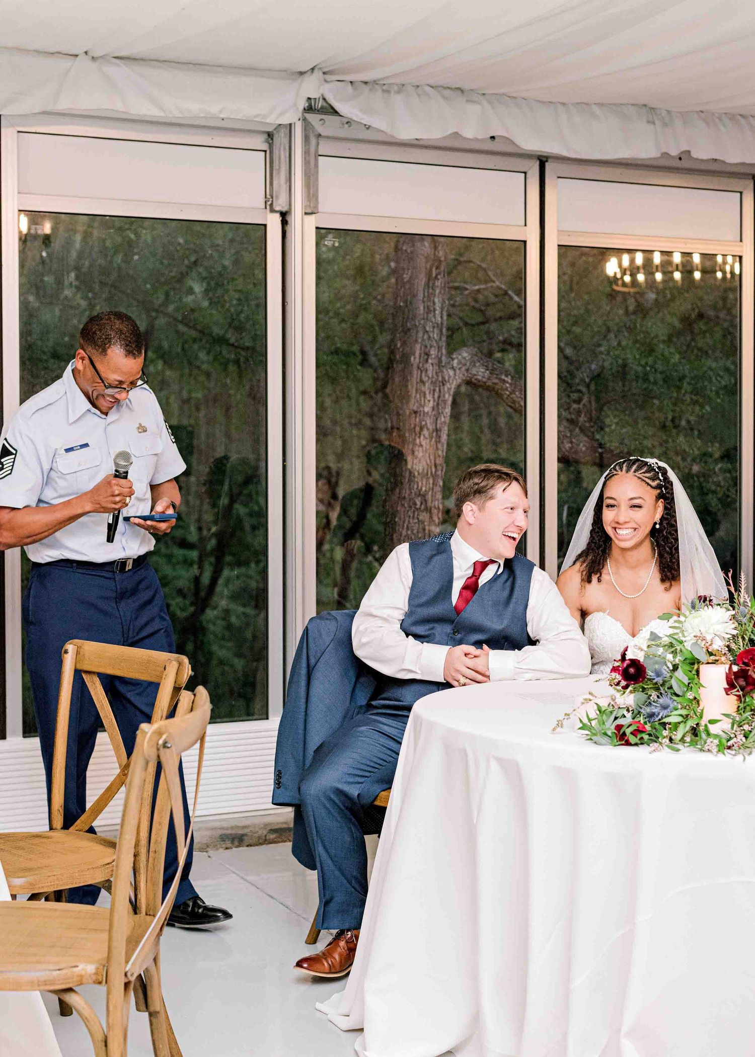 Wedding reception scene at an enclosed outdoor venue with glass windows.