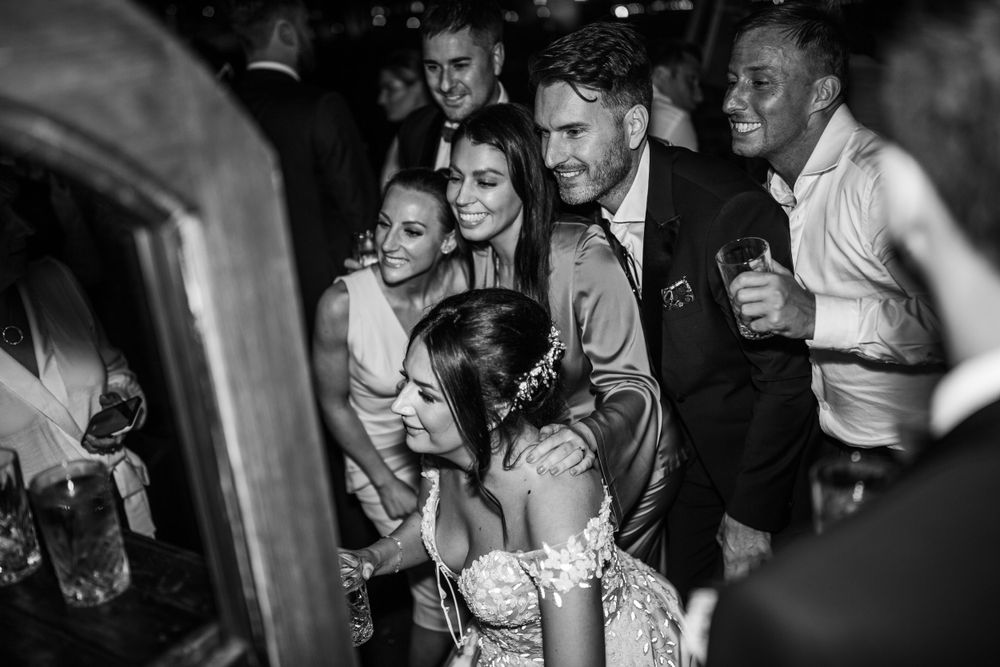 Wedding guests laughing and dancing during reception celebration in black and white.