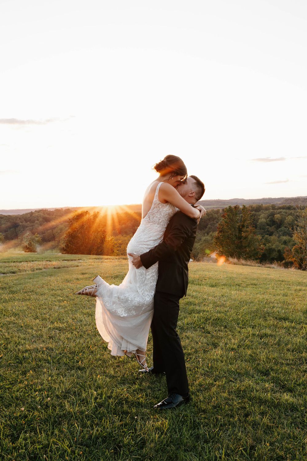 Groom lifting bride at golden hour