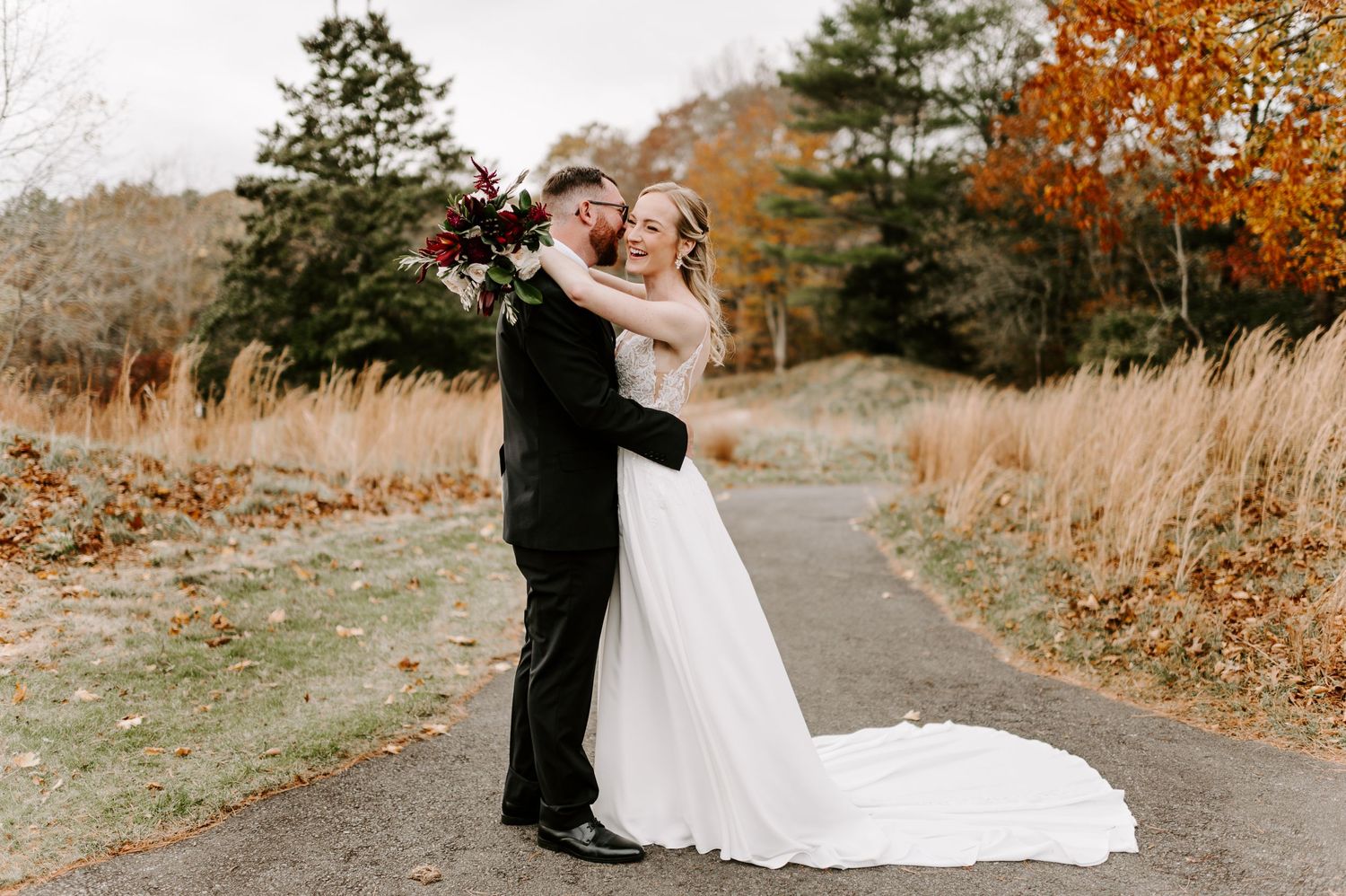 Dancing couple embracing on outdoor path with autumn scenery.