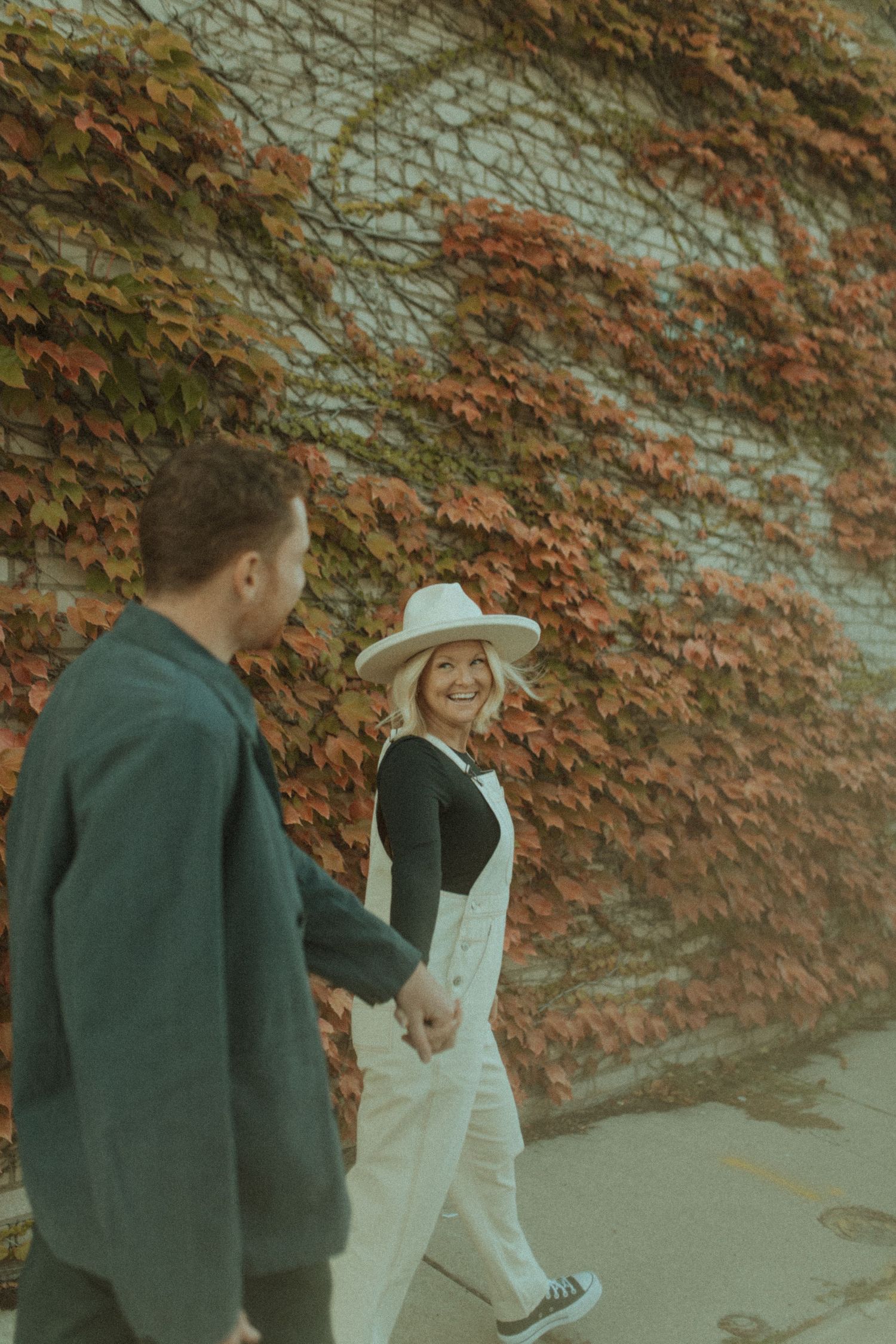 Couple walking together along ivy covered wall in autumn.