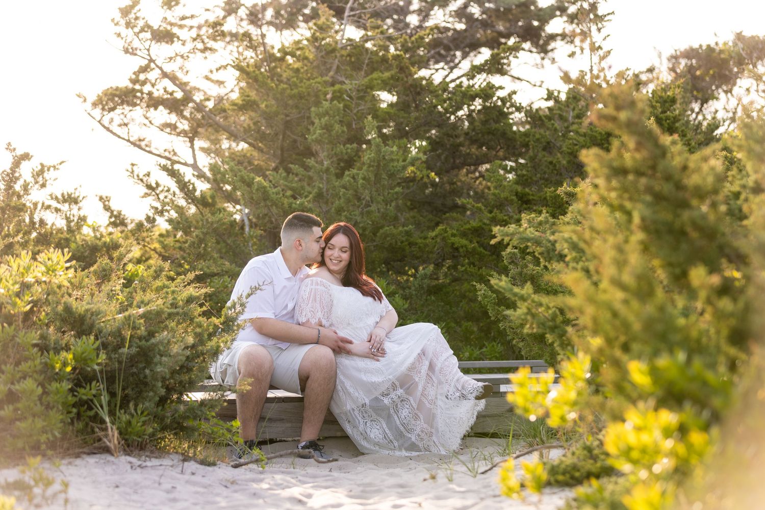 A couple shares an intimate moment on a beach during sunset for their engagement photos.