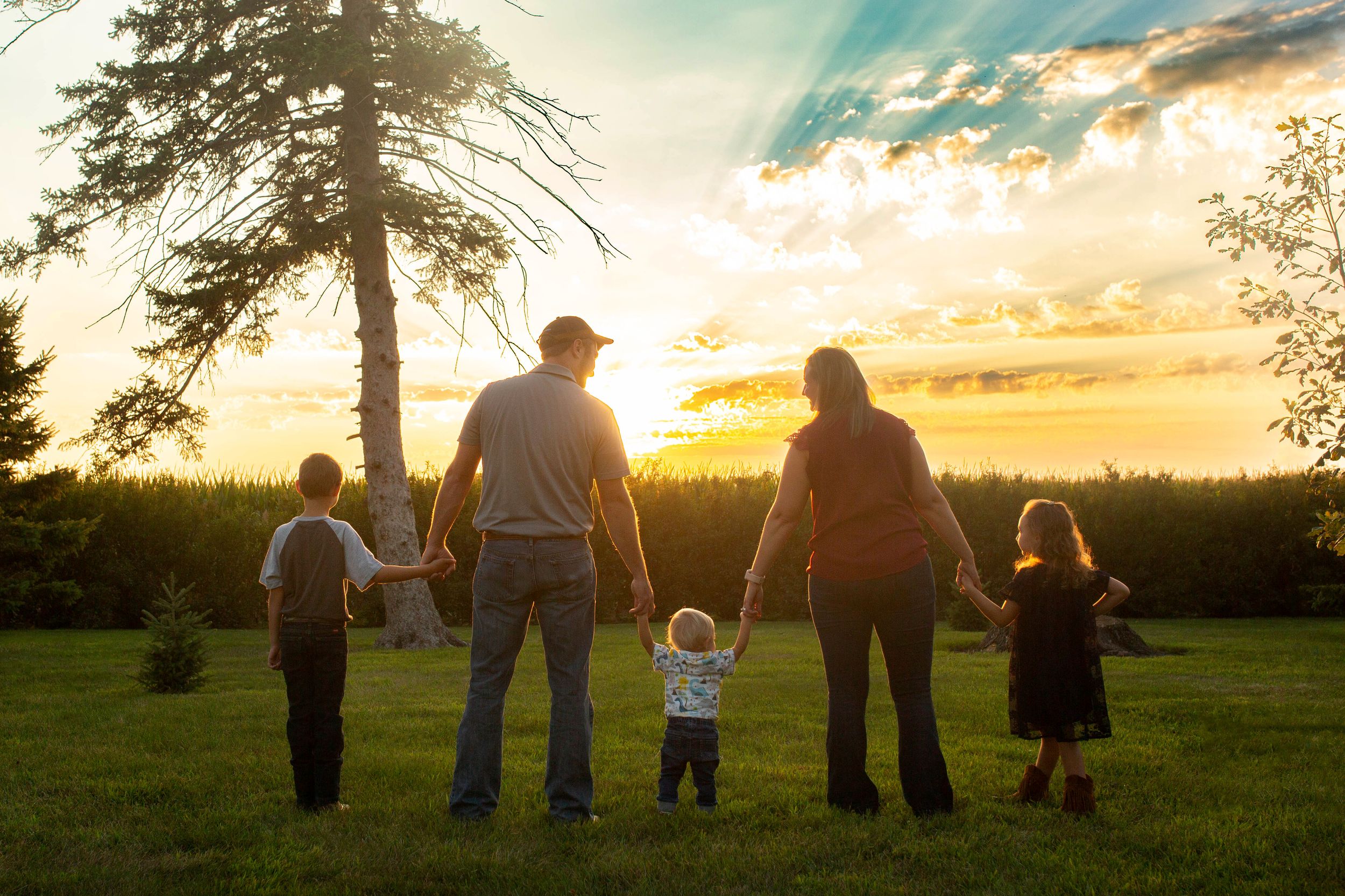 Iowa farm family walking through a field at sunset, capturing the warmth and connection of rural life