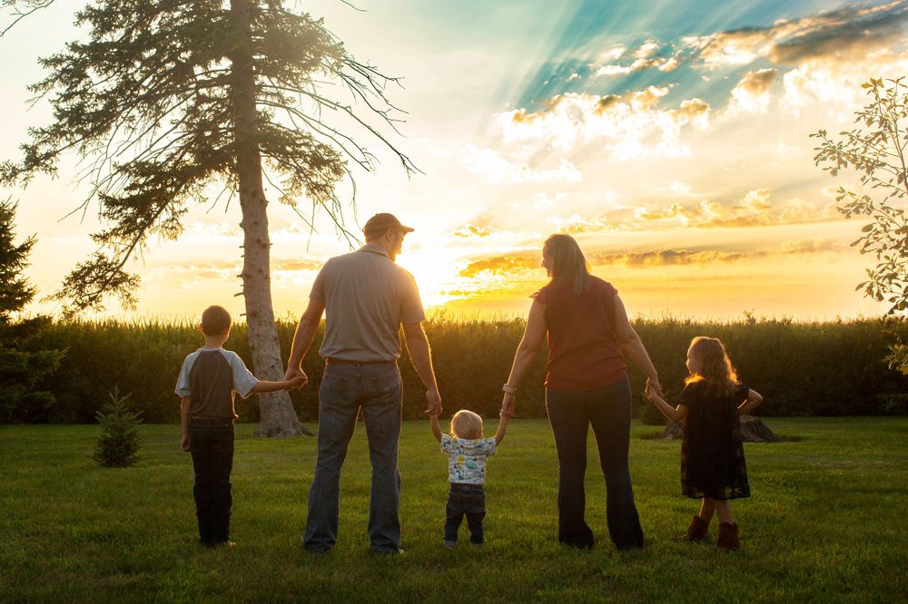 Iowa farm family walking through a field at sunset, capturing the warmth and connection of rural life