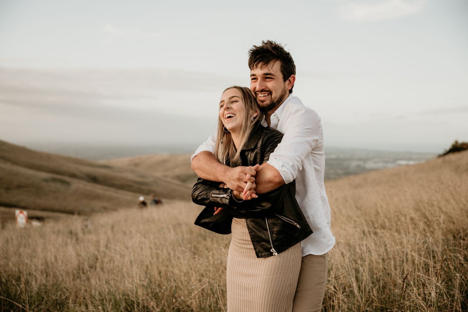 Romantic embrace on a hilltop meadow with rolling hills in the background.