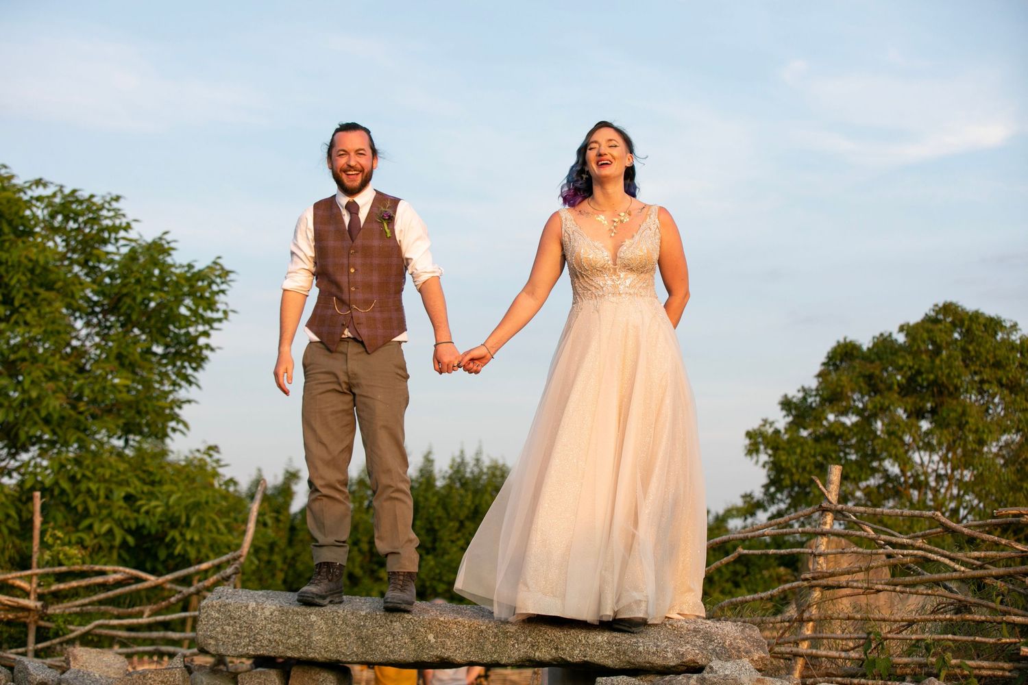 Wedding couple posing outdoors against natural landscape during golden hour.