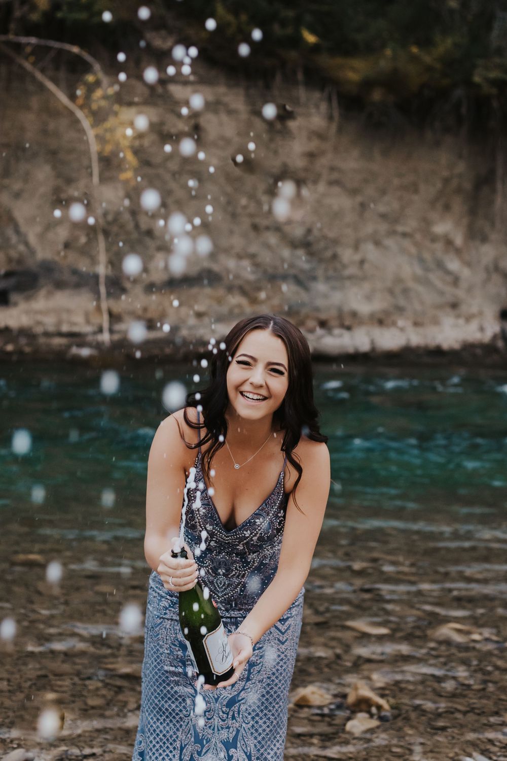 Girl in dress sprays champagne towards camera