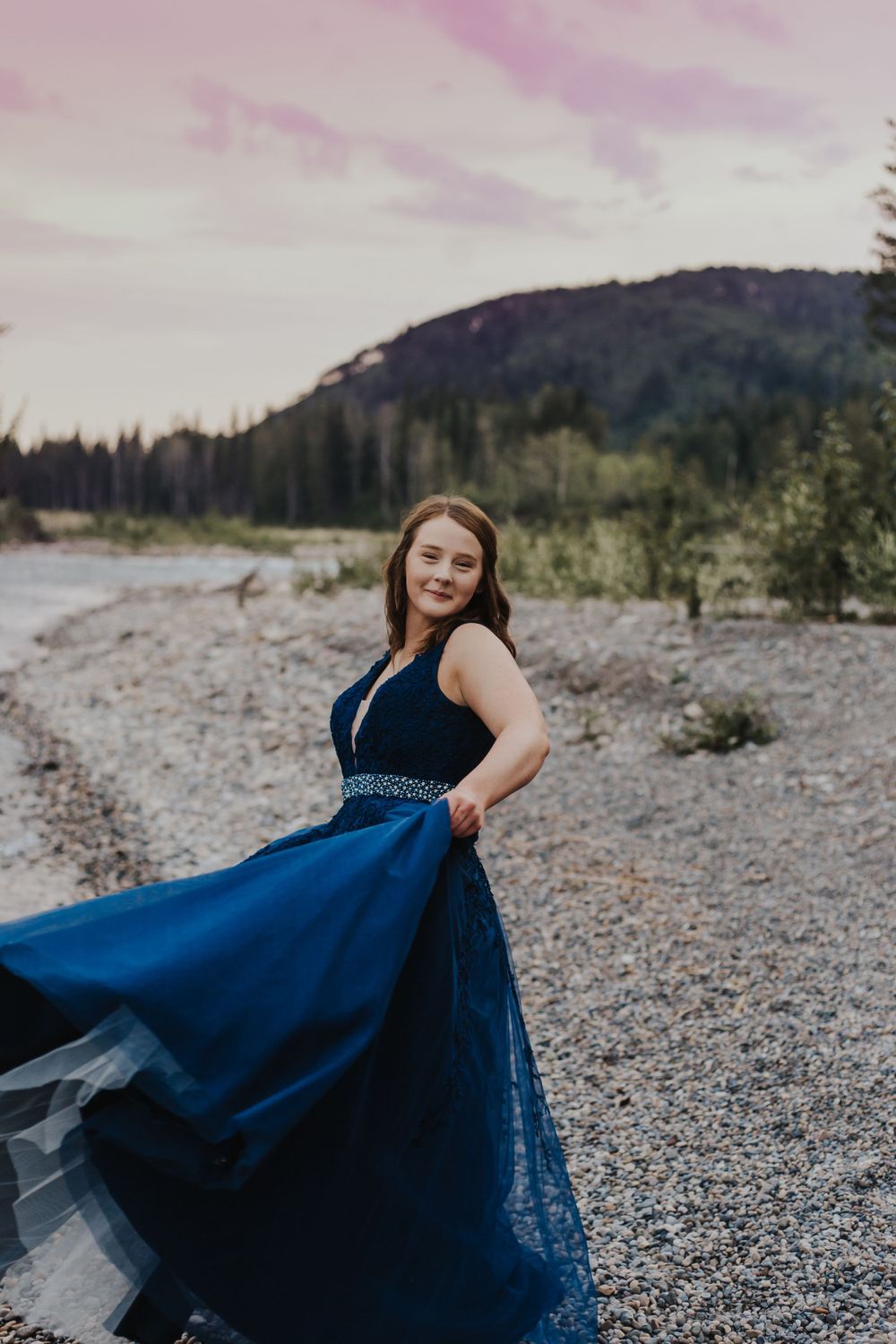 Girl twirls in navy blue dress by a river