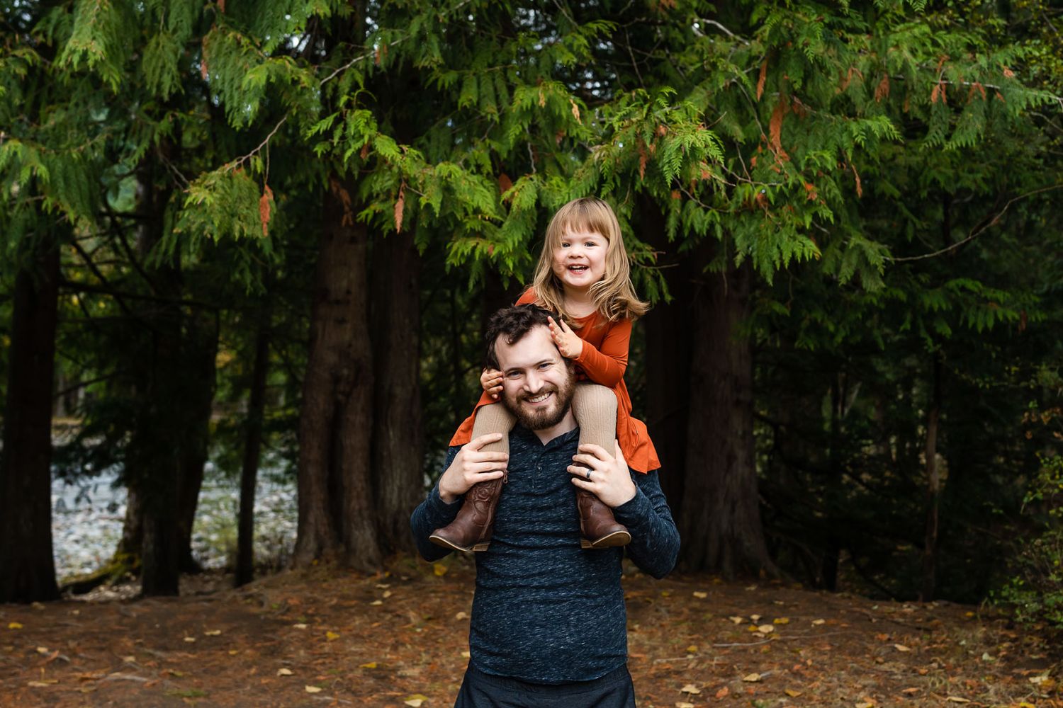 Daughter on dad's shoulders, laughing, during fall family photos.