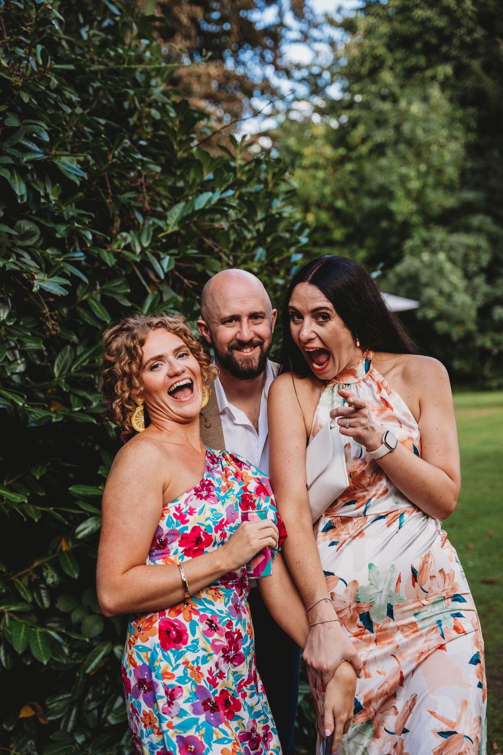 Group laughing together during outdoor summer celebration in garden setting.