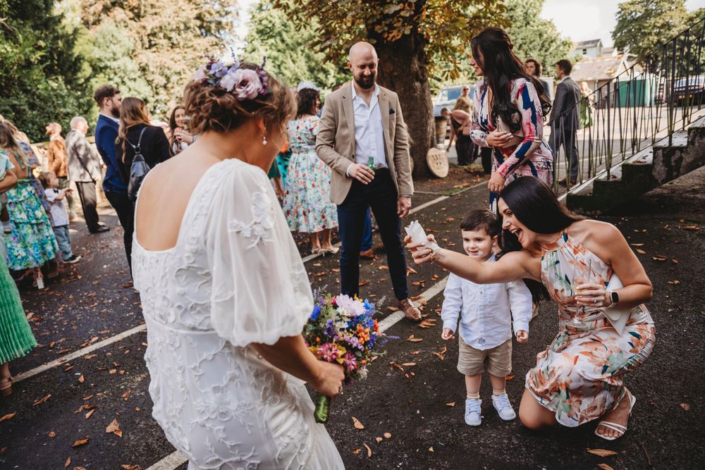 Outdoor wedding celebration with guests mingling in garden setting.
