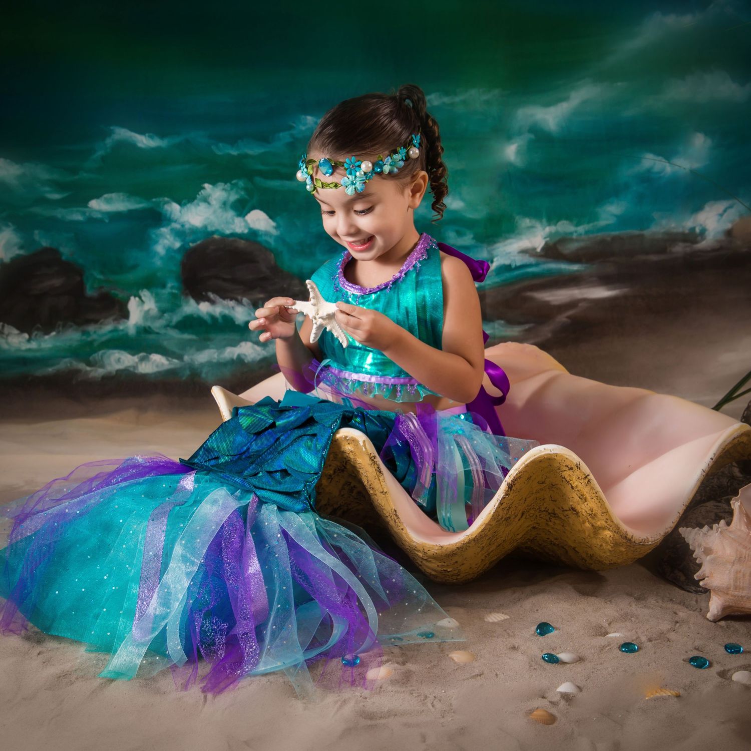 Coastal fantasy portrait series featuring turquoise and purple tulle dress on sandy beach.