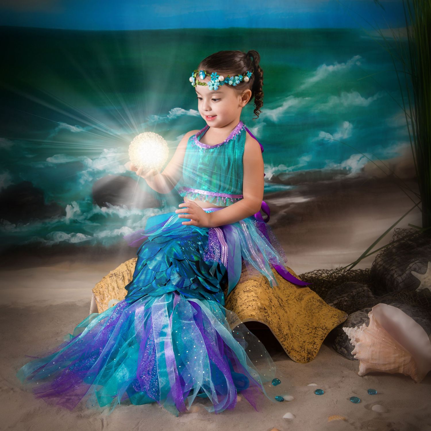 Magical seaside photoshoot featuring glowing light effects and flowing turquoise costume.