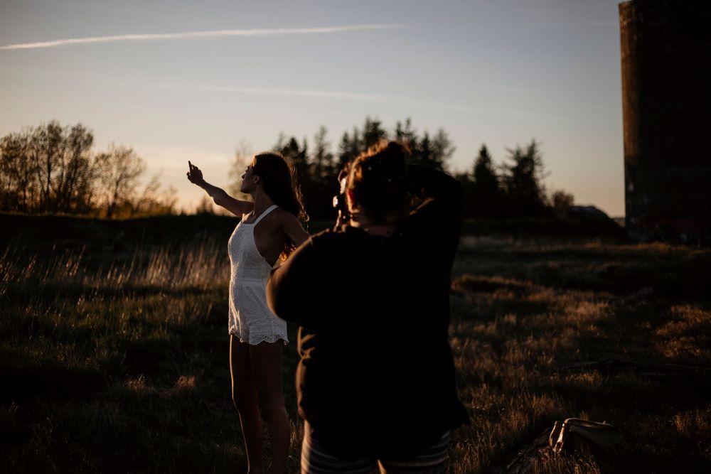 Silhouettes of people posing at sunset with dramatic sky backdrop.