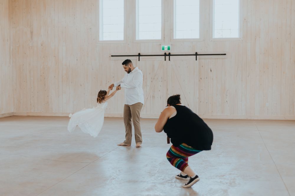 A photographer captures a couple in a bright, minimalist indoor space with white walls.