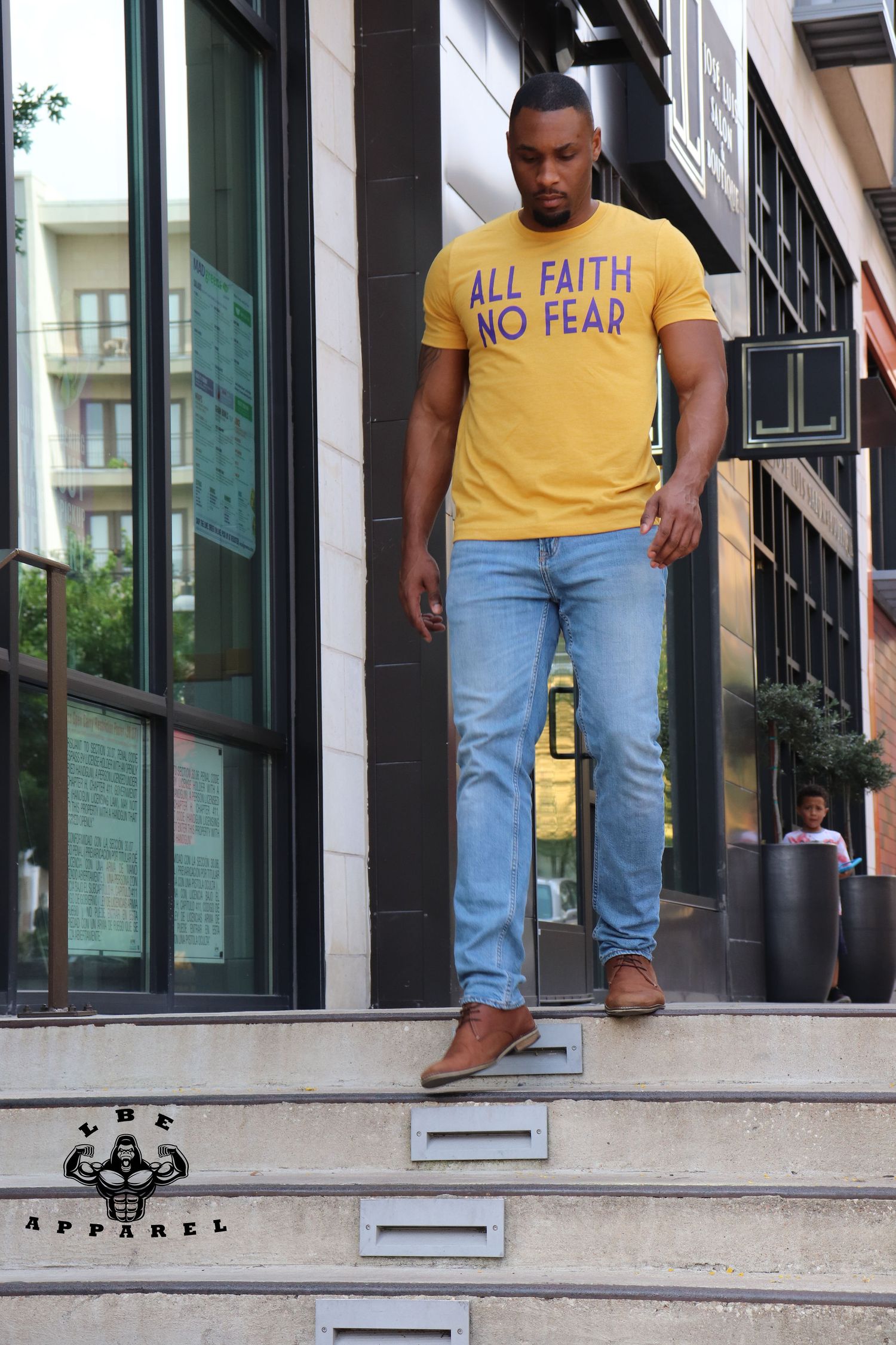 Person wearing yellow 'All Faith No Fear' t-shirt walking down concrete steps.