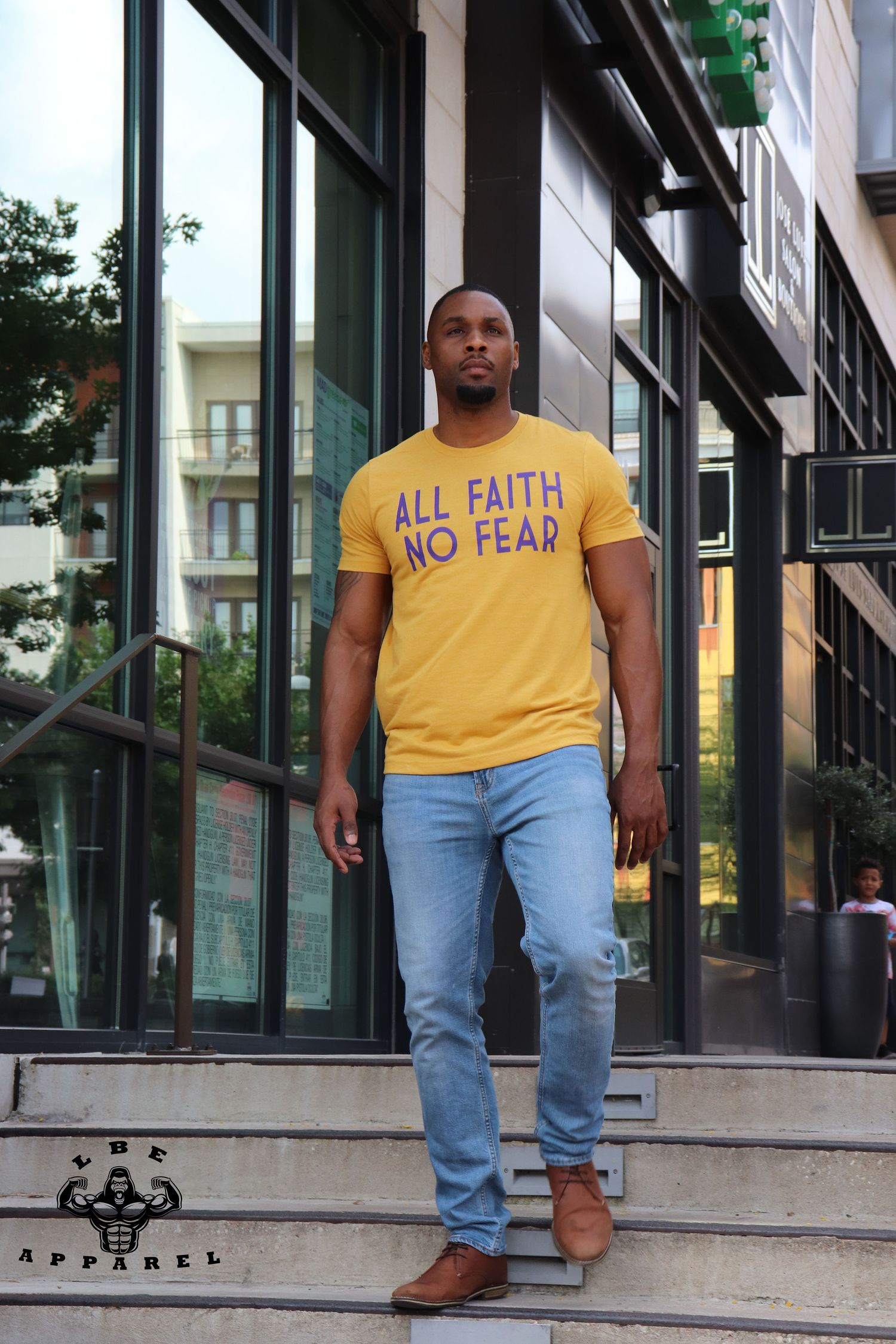 Urban fashion photo featuring yellow motivational t-shirt and light denim jeans on steps.
