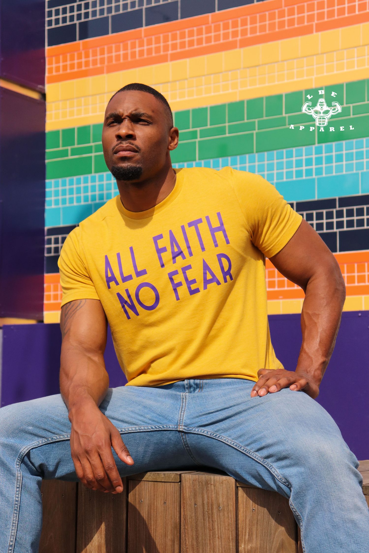 Fashion photo against colorful rainbow wall backdrop featuring yellow statement t-shirt.