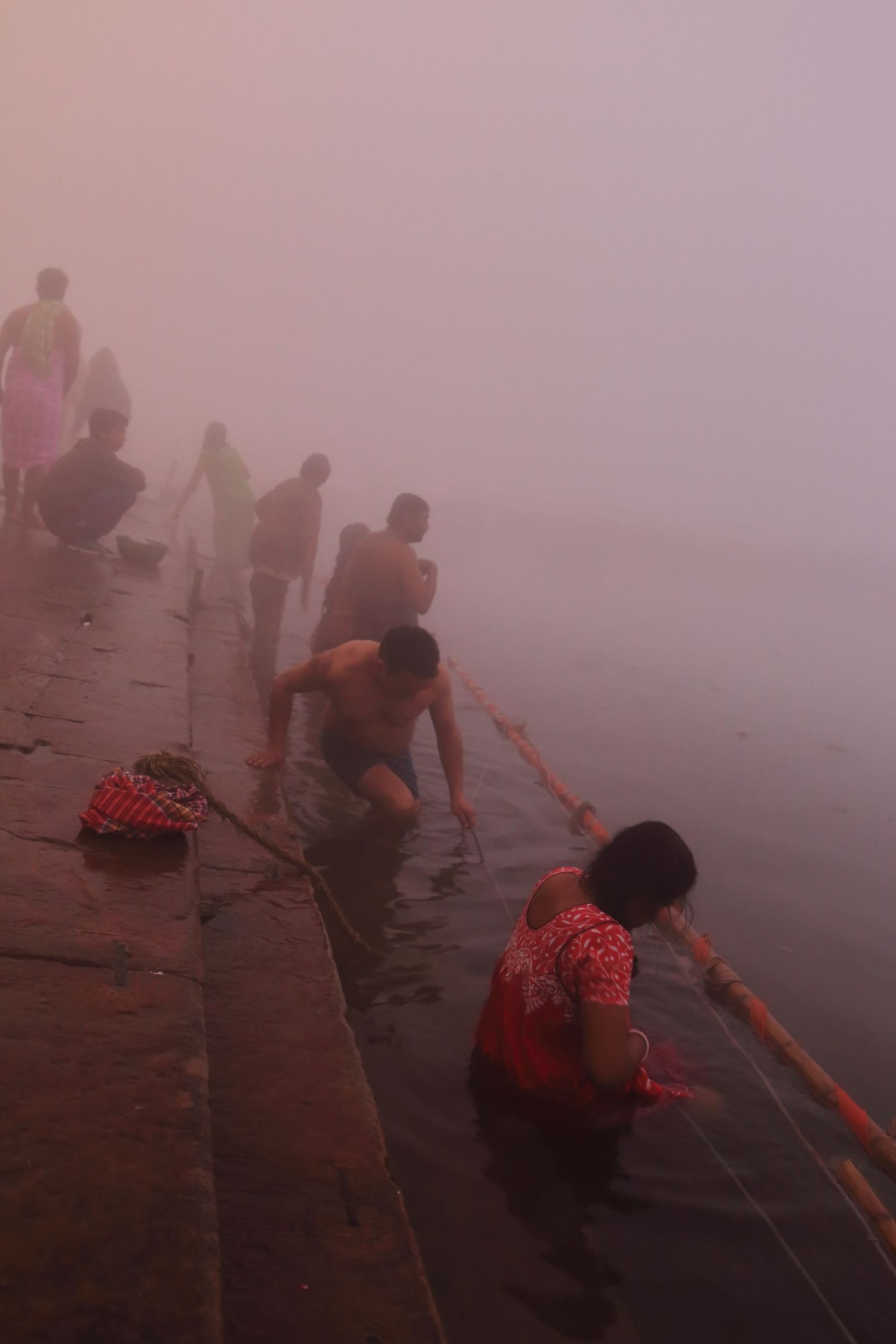 Misty morning ritual at the ghats of Varanasi with people performing ceremonies by the water.