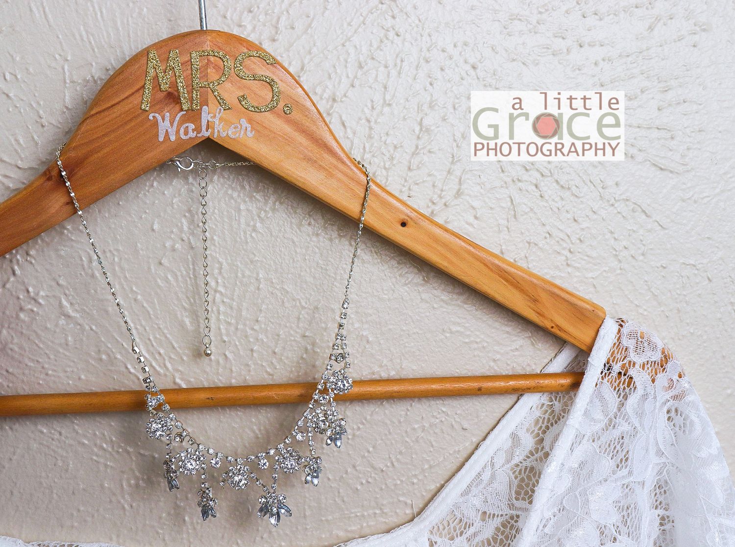 Wedding accessories including jewelry and hangers arranged against a white wall.