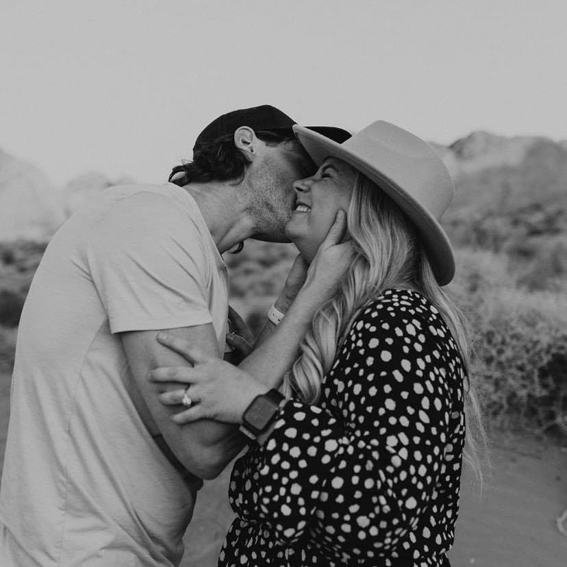 Black and white romantic couple portrait in desert landscape wearing casual attire.