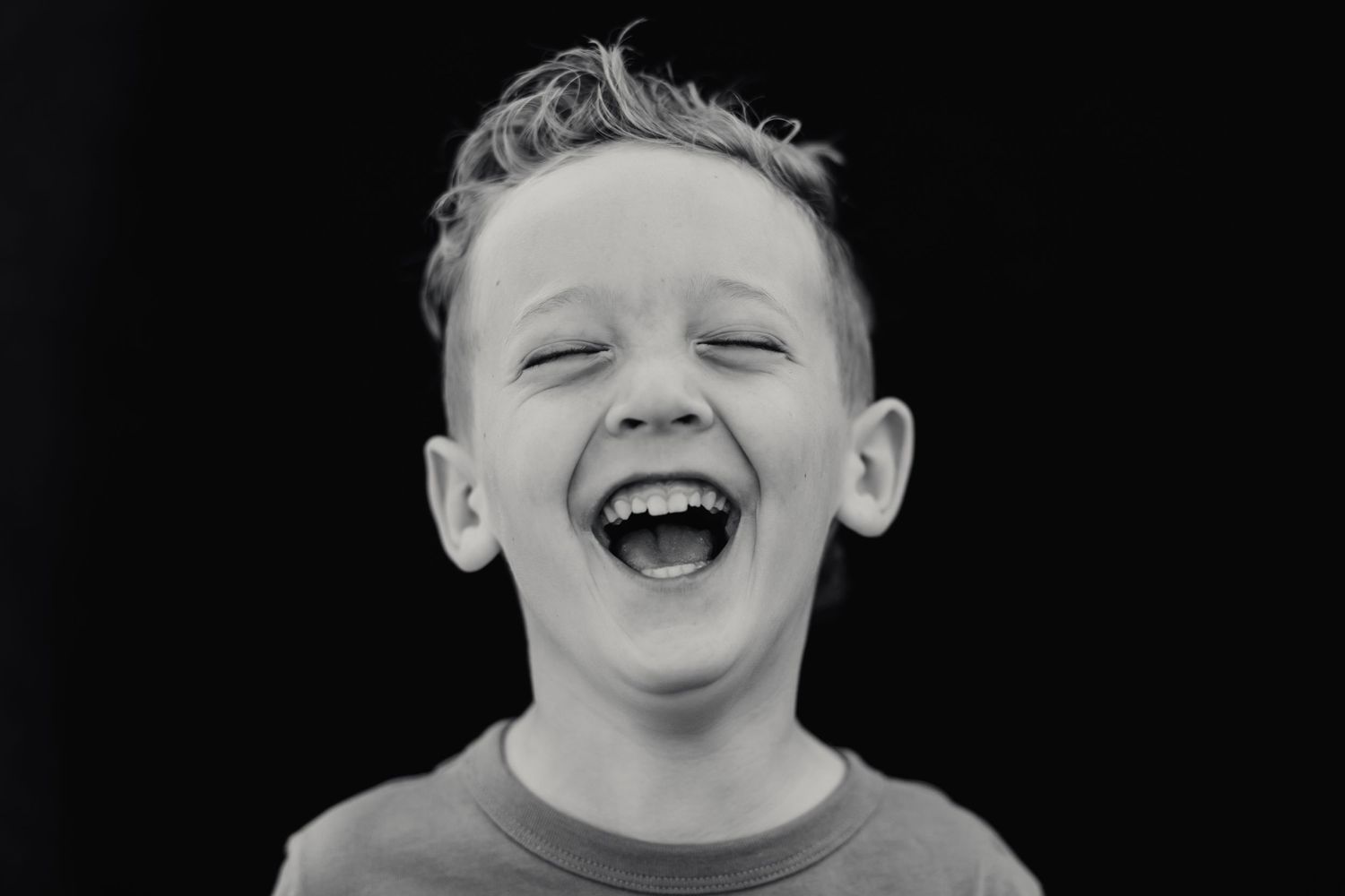 A black and white headshot capturing pure laughter and joy.