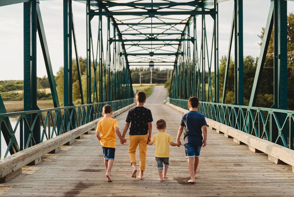 Family members walking together on historic green metal bridge during daytime.