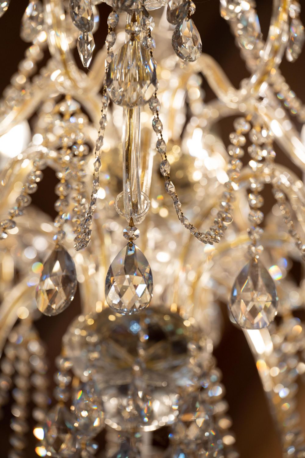 Crystal chandelier with teardrop-shaped crystals sparkling against a dark background.