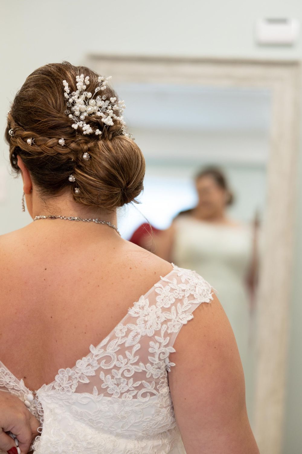 Elegant bridal hairstyle with pearl accessories and lace dress detail.