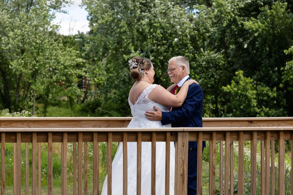 A tender moment is shared between a couple in wedding attire on a wooden deck.
