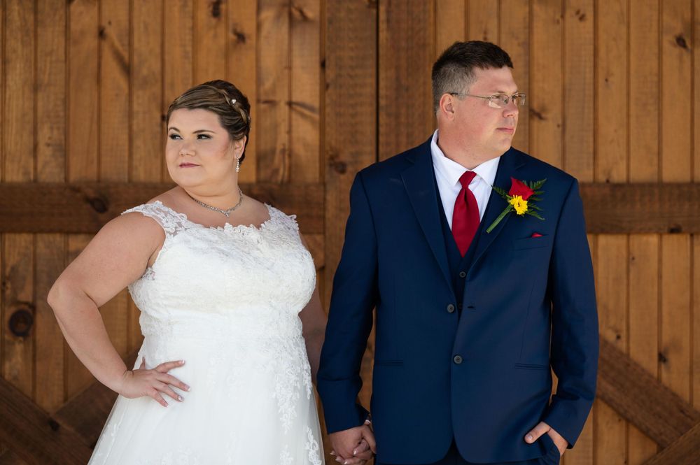 Wedding portrait in front of a rustic barn door with navy suit and white gown.