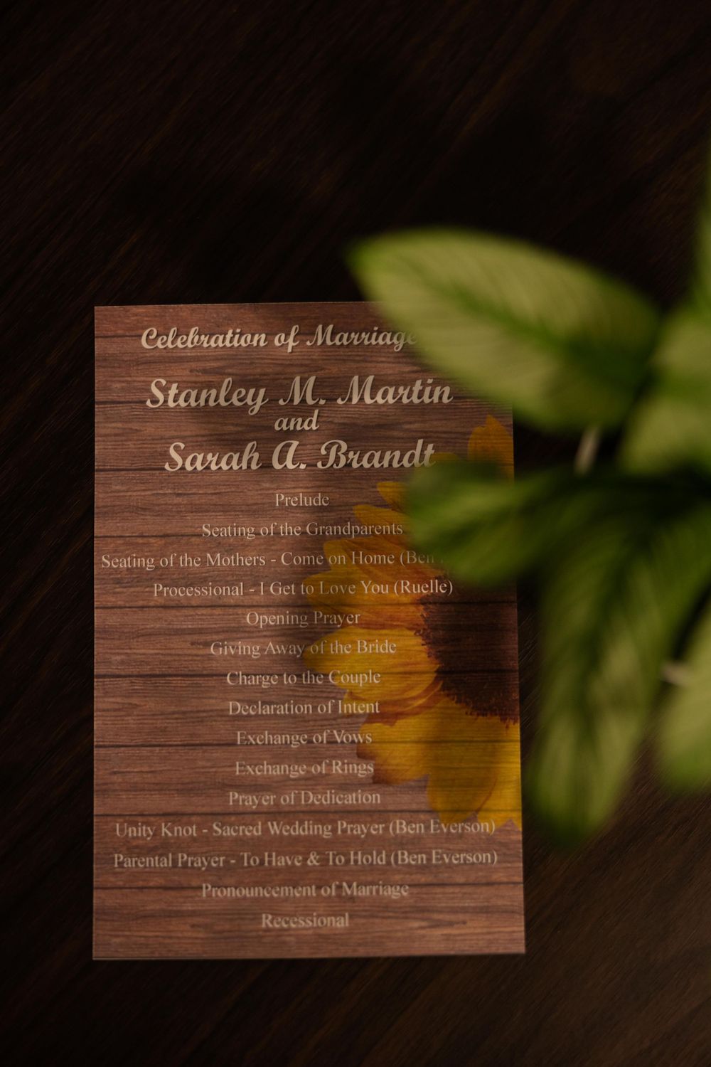 Wooden wedding program listing ceremony details for Stanley and Sarah's celebration.
