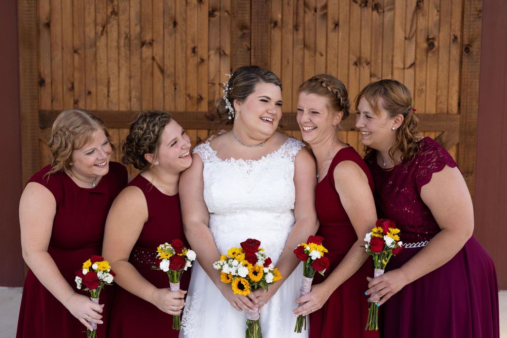 Bridal party shares intimate moment while holding vibrant sunflower bouquets.
