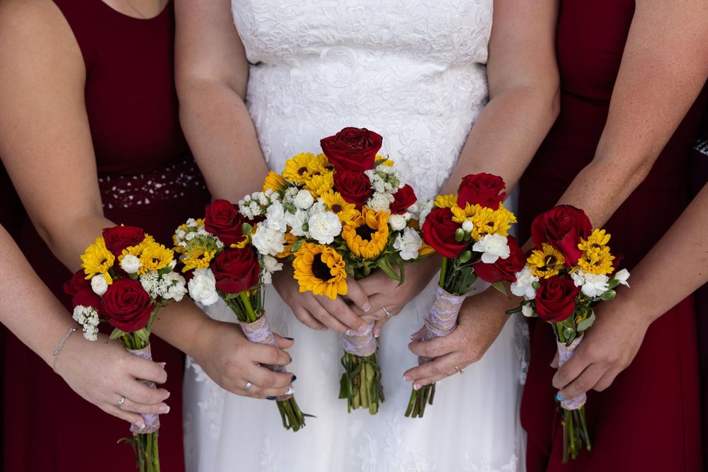 Close-up of wedding bouquets featuring red roses, sunflowers, and white daisies.