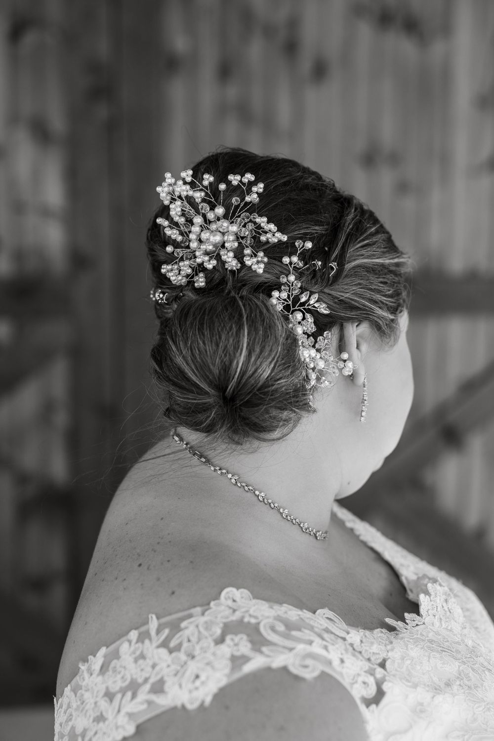 A black and white detail shot of delicate pearl hair accessories and lace dress neckline.