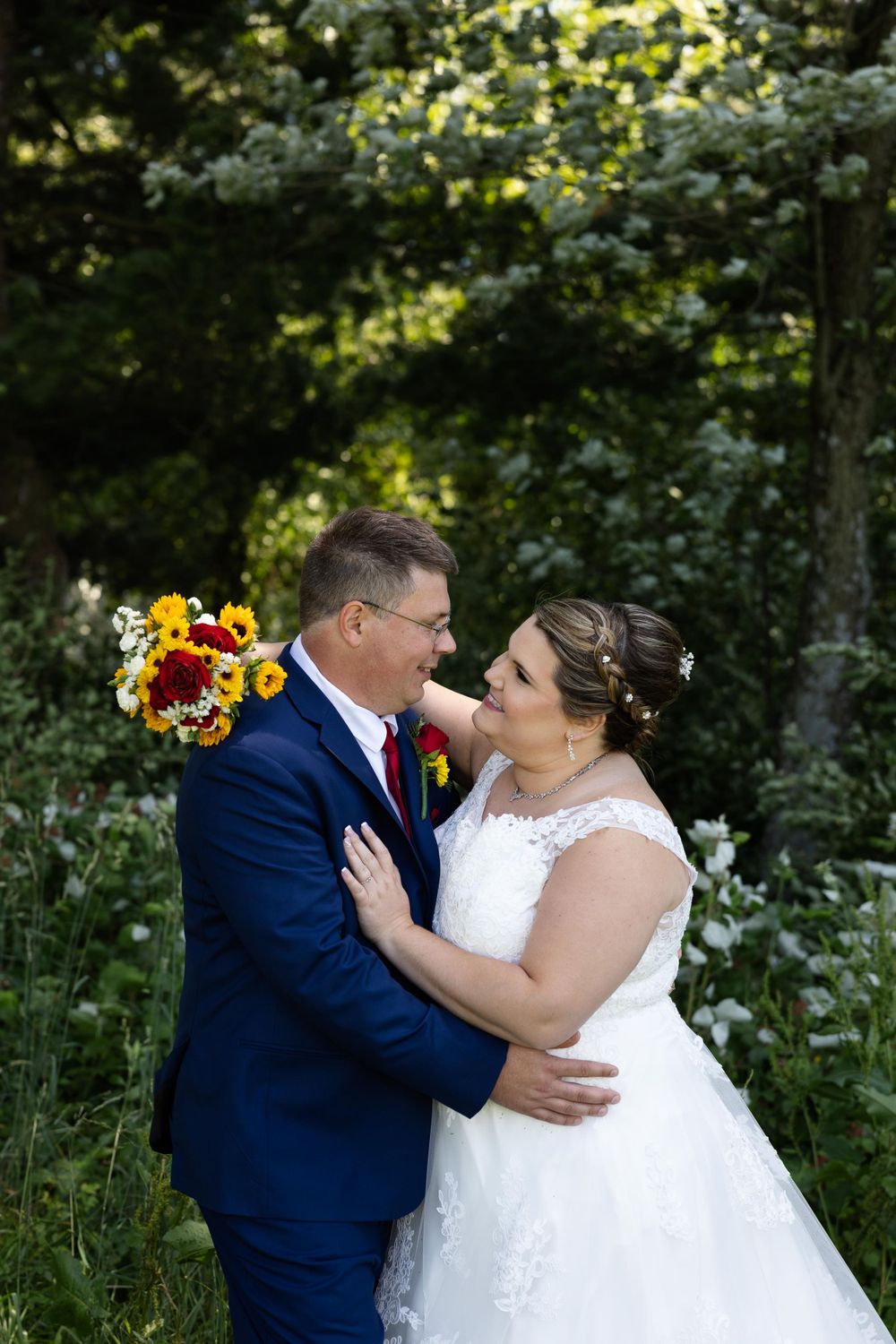 Couple shares intimate moment in garden with vibrant sunflower bouquet.