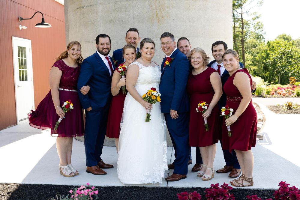 Wedding party poses on white steps with burgundy bridesmaids dresses and navy suits.