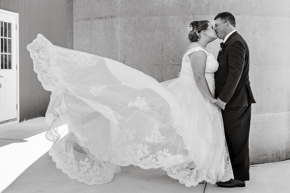 Dramatic black and white photo with flowing veil against concrete wall.