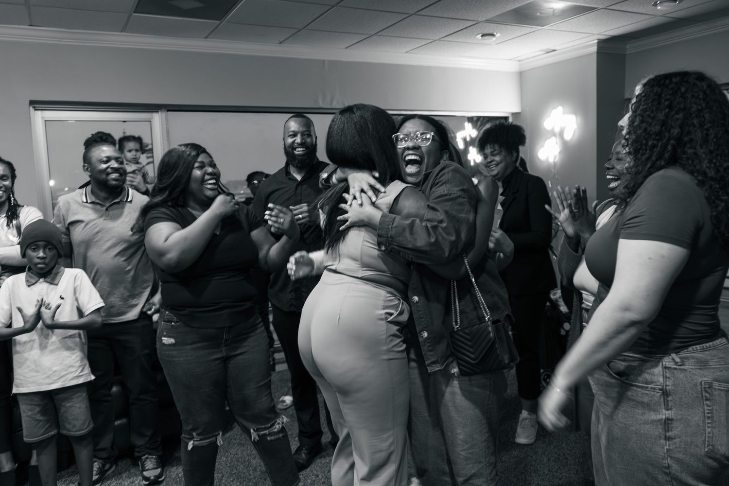A joyous celebration with a group of people laughing and hugging in a room.