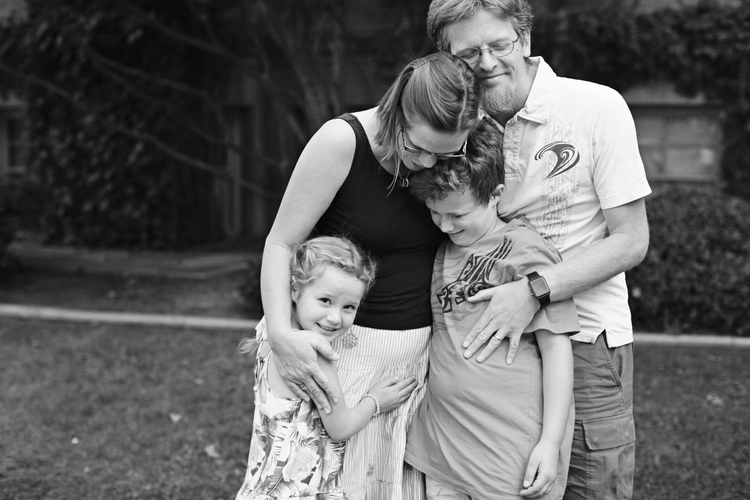 A black and white family portrait showing tender moments outdoors.