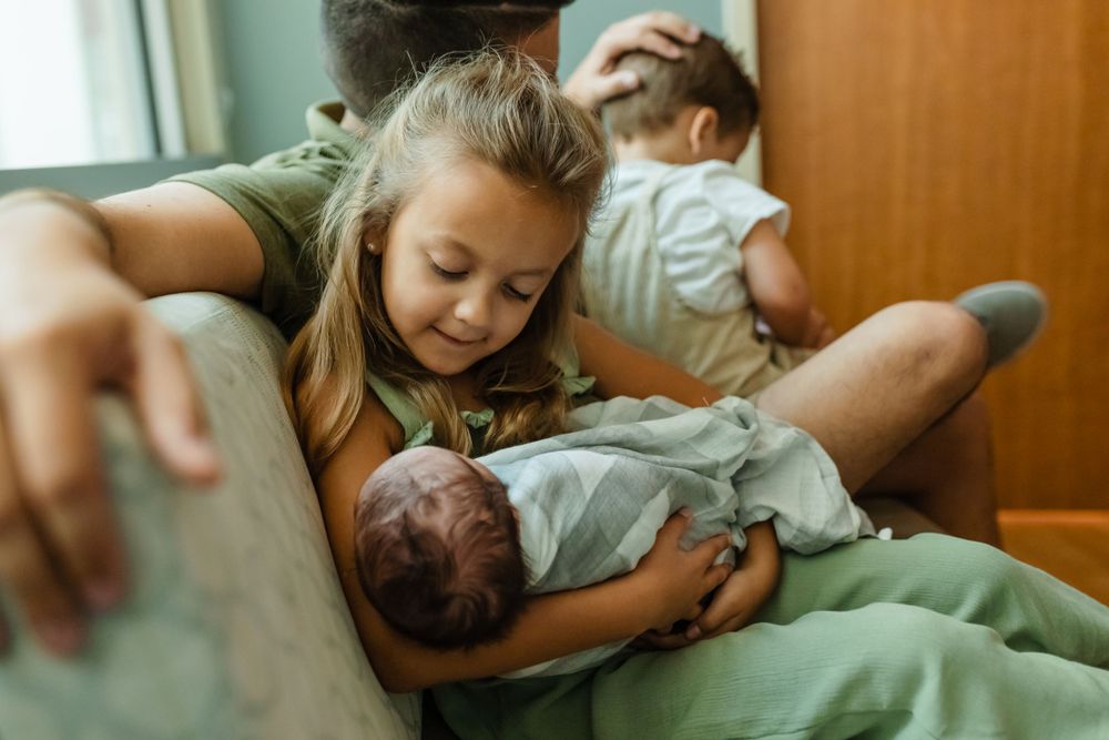 A girl holding their baby brother in the hospital during a fresh 48 portrait session.